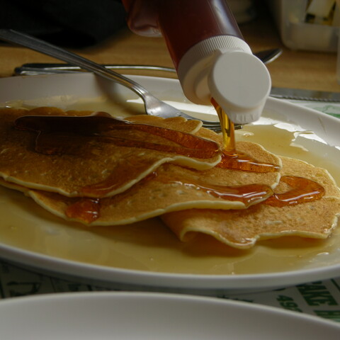 Maple syrup being poured on pancakes at Moore's Pancake House